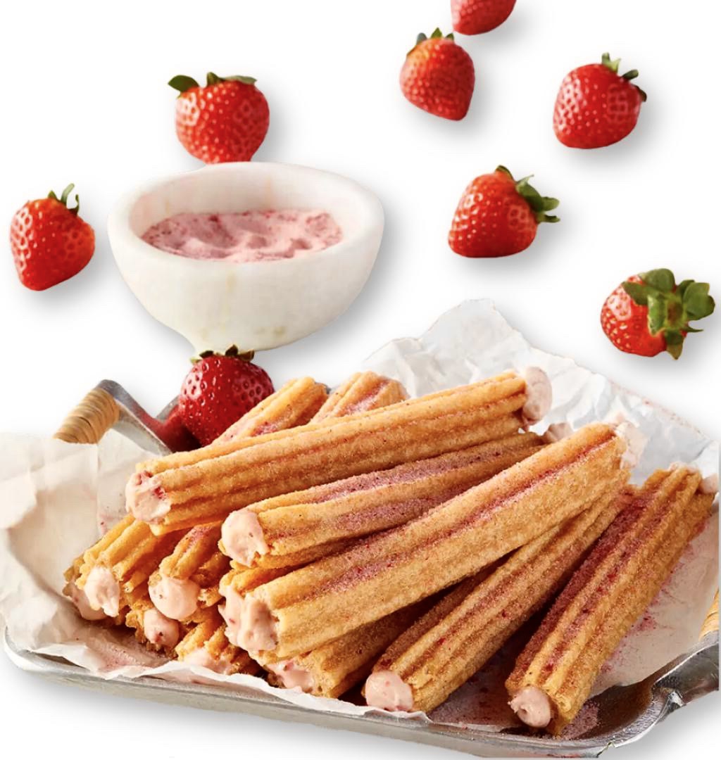 A plate of churro with strawberries and dipping sauce.