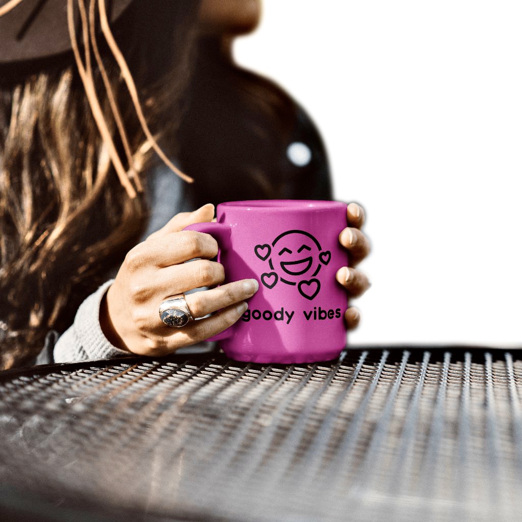 A woman holding a pink coffee mug on top of a table.