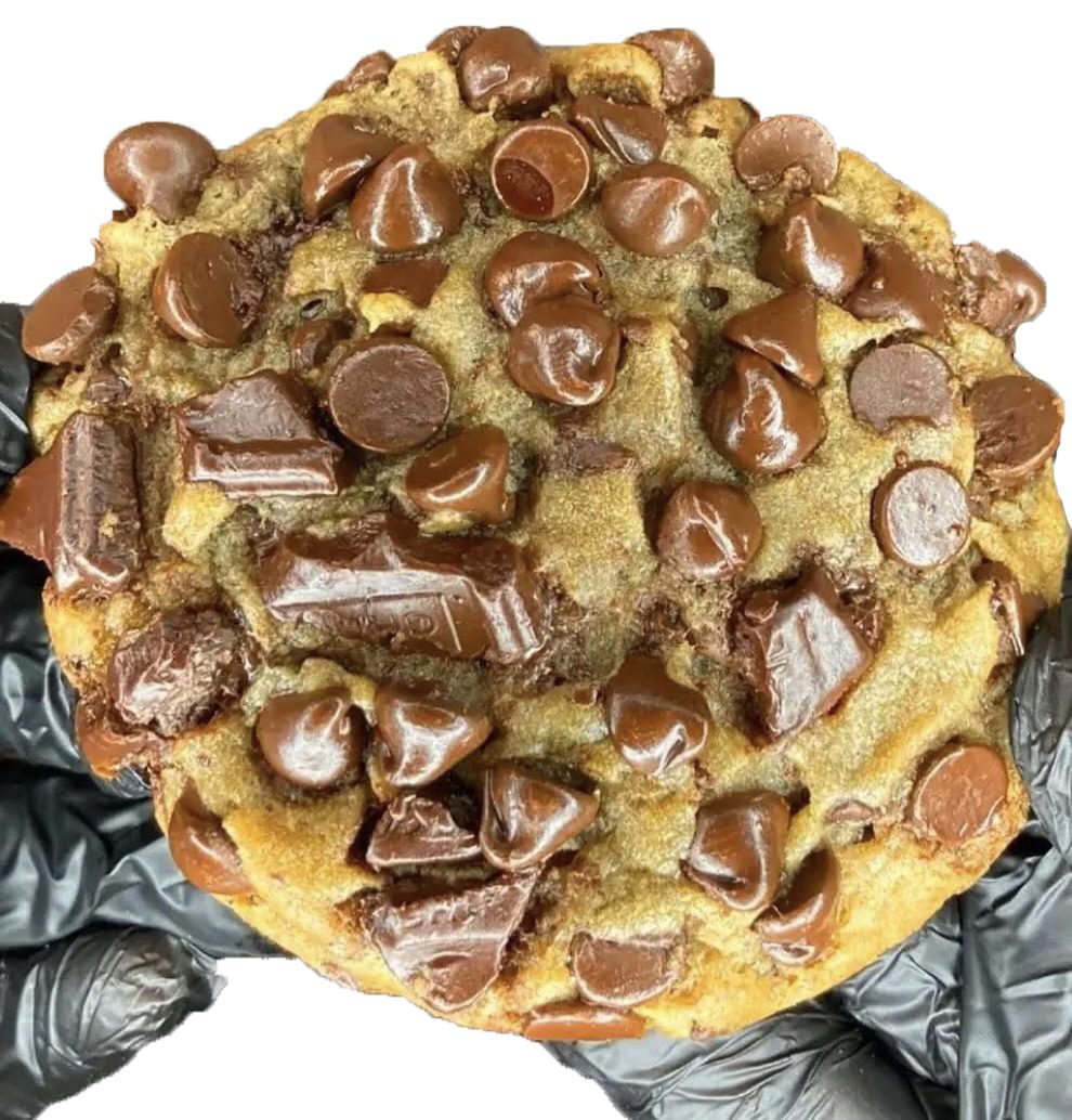 A person holding a chocolate chip cookie with toppings.