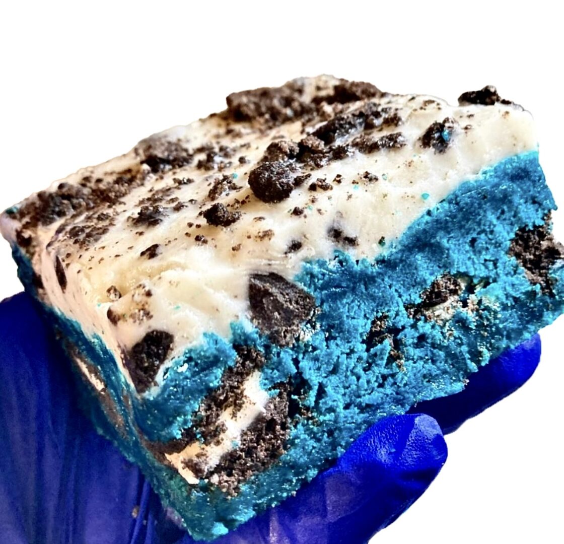 A piece of cake with blue icing and cookies.