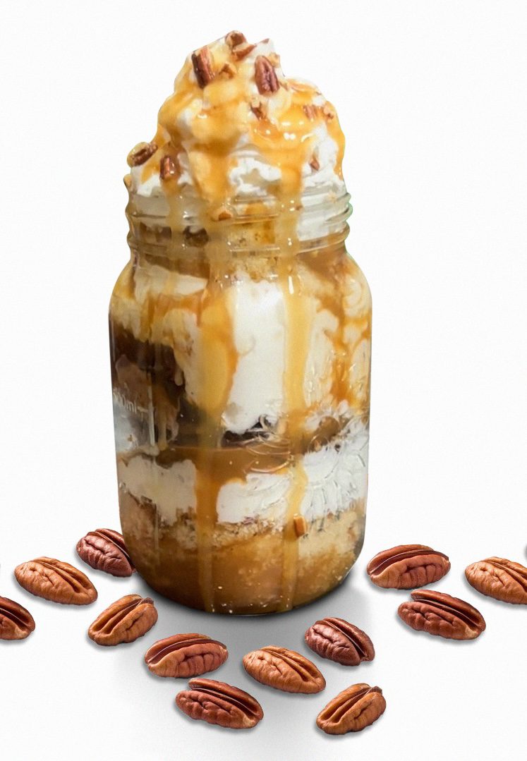 A jar of dessert with whipped cream and caramel.
