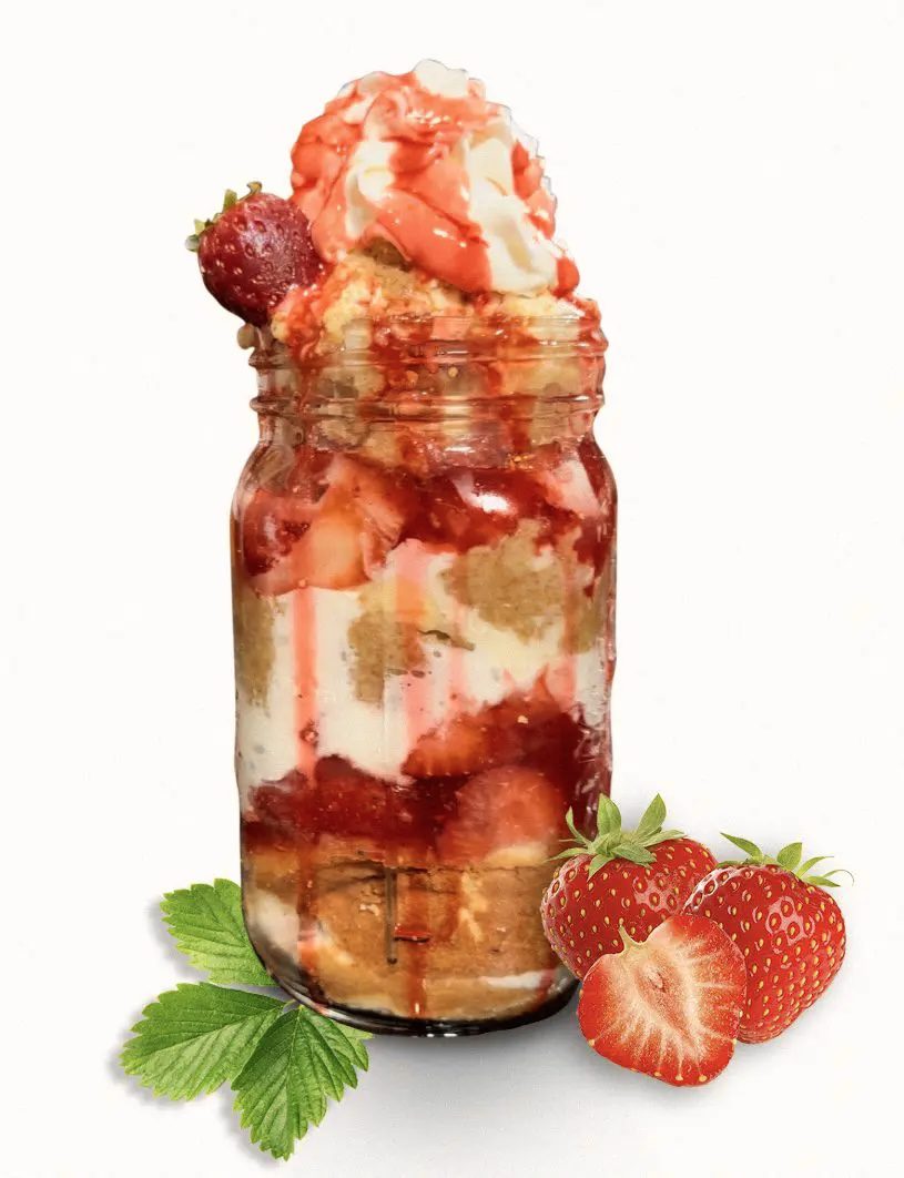 A jar of strawberries and cream with some leaves