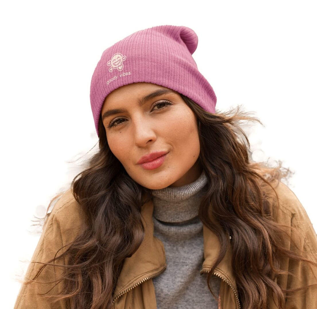 A woman wearing a pink beanie and brown jacket.